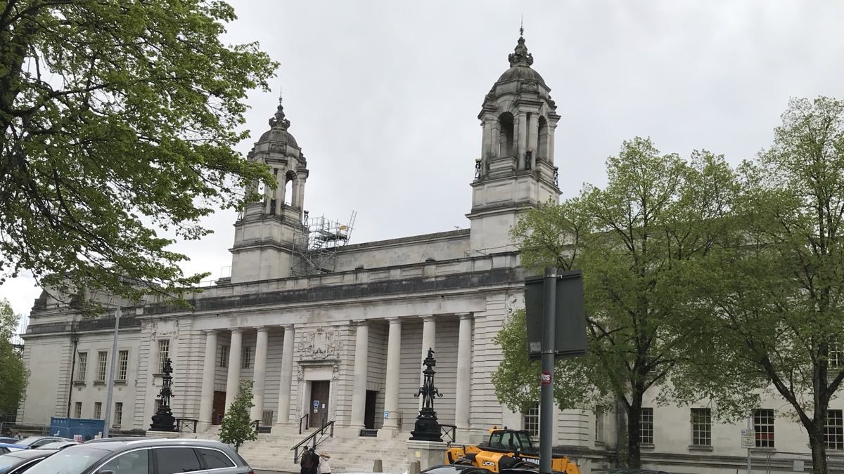 The Portland stone frontage of Cardiff Crown Court on King Edward VII Avenue, with its colonnaded entrance and twin domed towers seen from across the road.