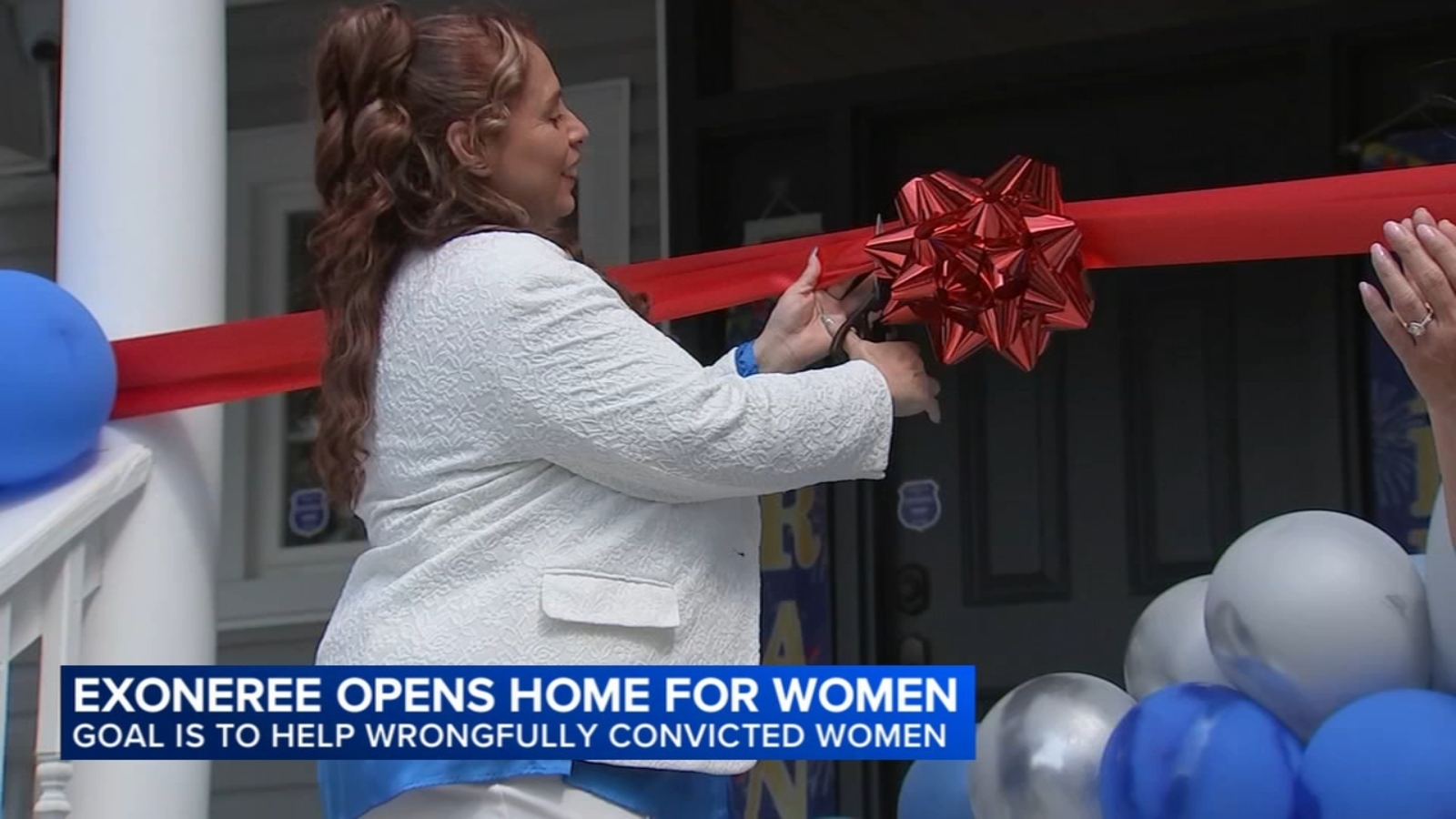 Marilyn Mulero cuts a red ribbon outside the Wrongful Conviction Trauma Center, surrounded by blue and silver balloons.