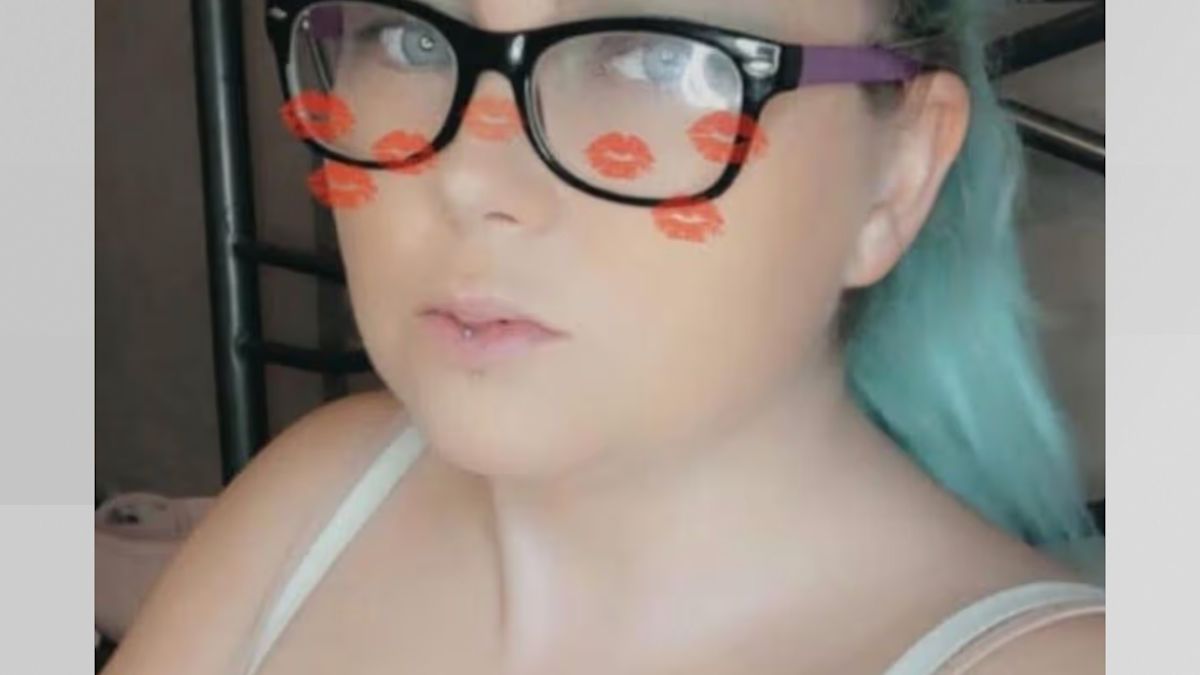 Stacey Sharples in a selfie, wearing dark-rimmed glasses, with a lip-print filter overlaid on the image.