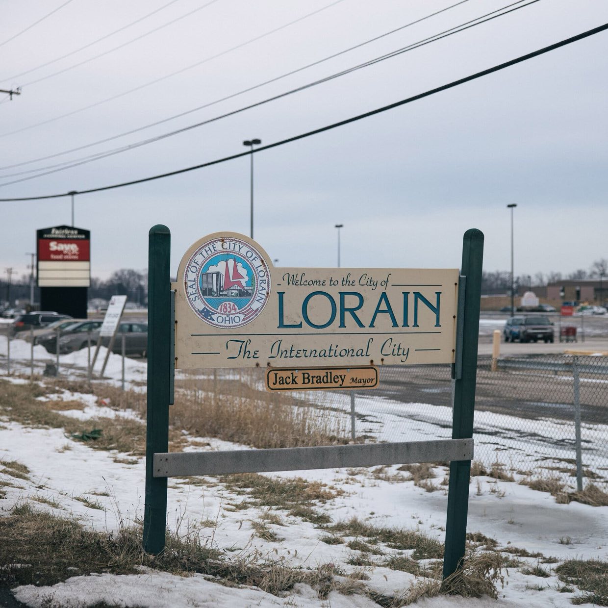 A sign in a snowy landscape by a store reads “Welcome to the City of Lorain.”