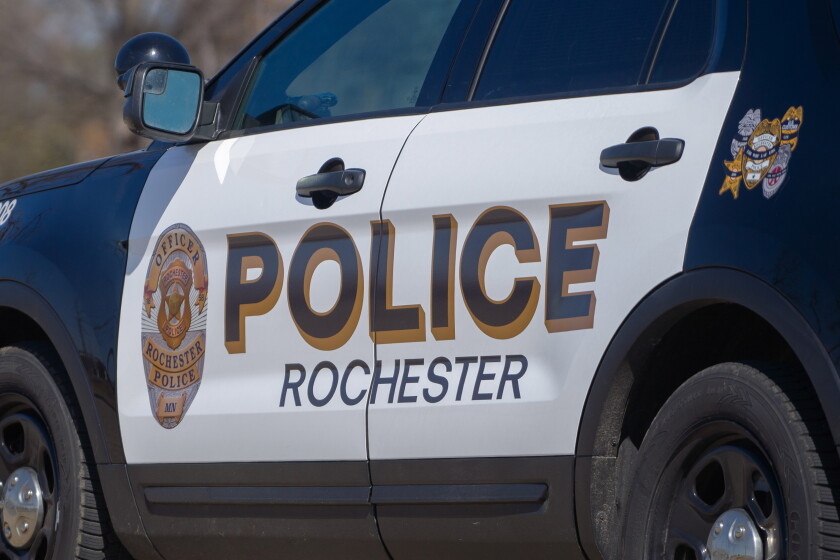 Close-up of the side of a Rochester Police Department SUV, a white door panel with POLICE in large gold-outlined letters above ROCHESTER and the department's badge.