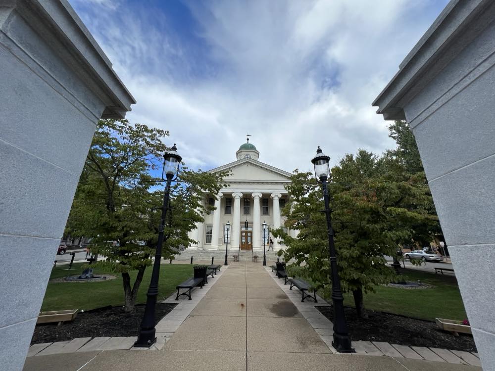 The Centre County Courthouse in Bellefonte, Pennsylvania, seen from a tree-lined walk between stone pillars