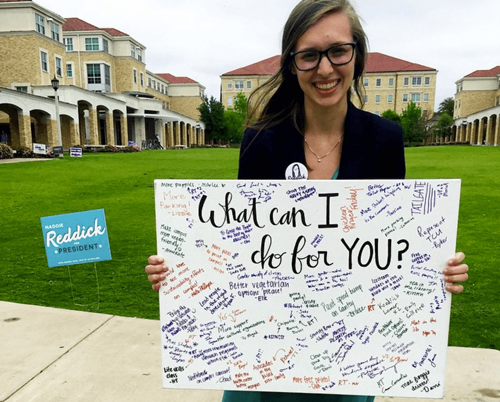 Madison Reddick as a TCU student-body presidential candidate, holding a sign reading “What can I do for YOU?” covered in handwritten notes