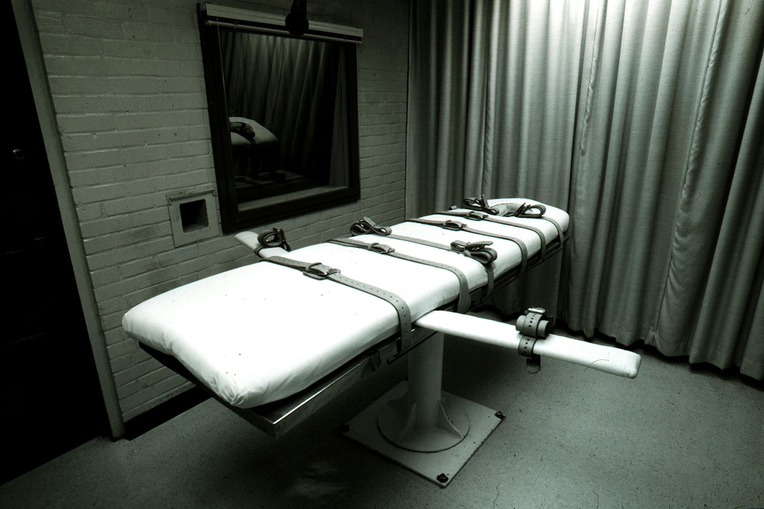 A death penalty room with an empty gurney and a viewing window.