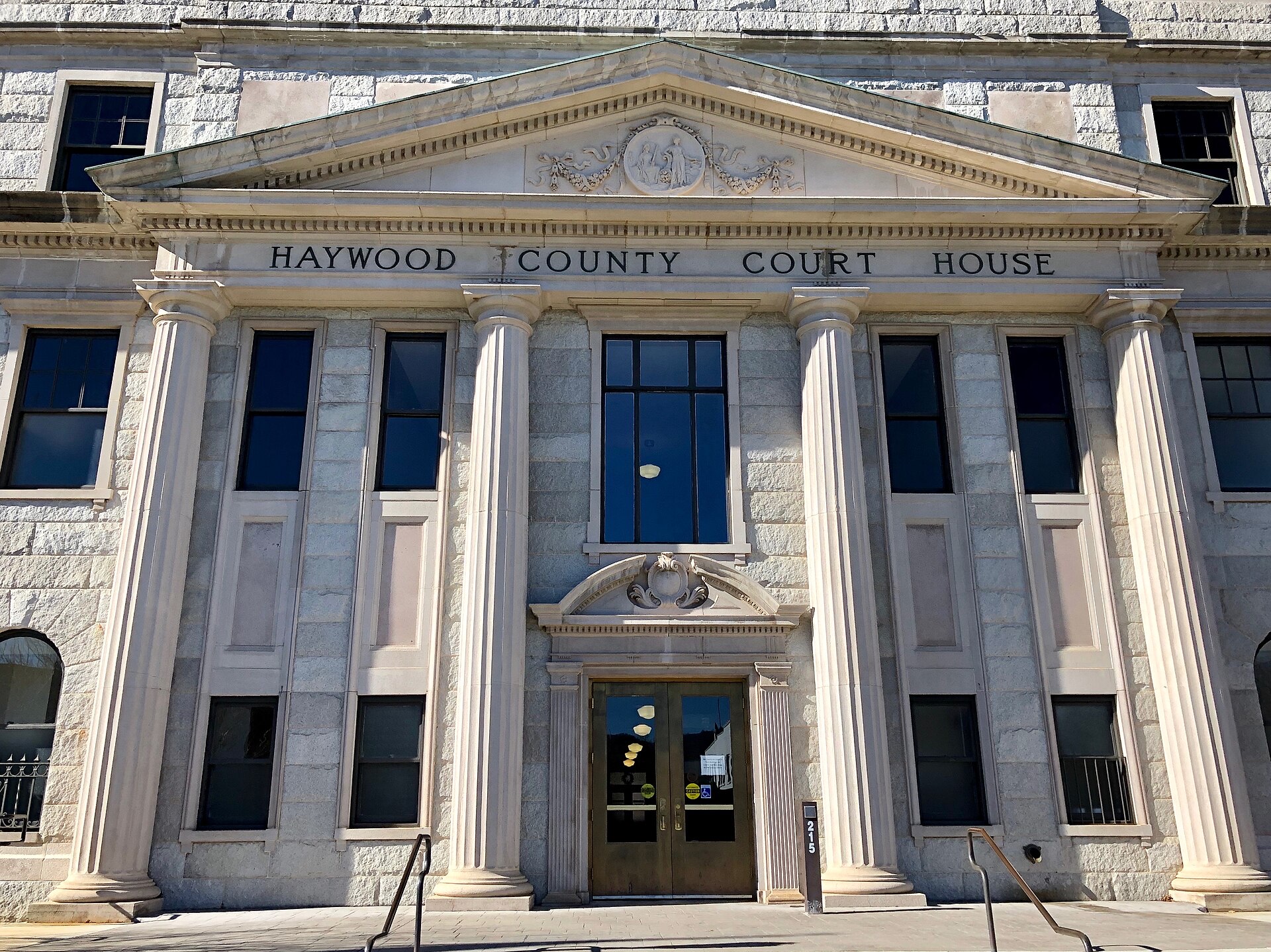 The stone portico of the Haywood County Courthouse in Waynesville, North Carolina, with four tall columns, a pediment and 'HAYWOOD COUNTY COURT HOUSE' carved above the entrance.